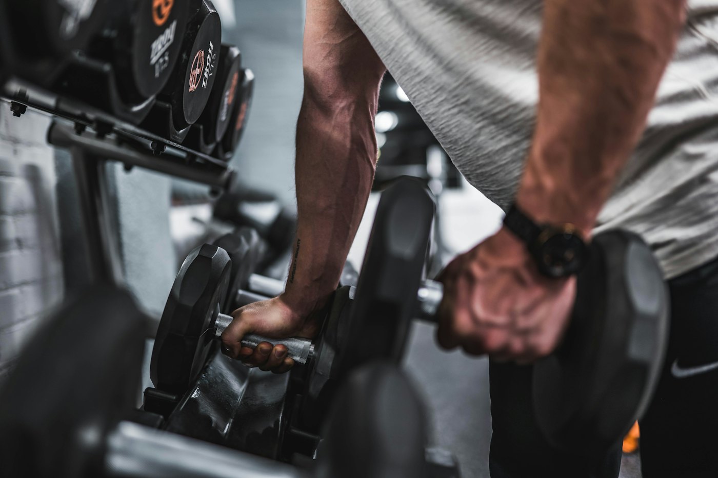 Hands lifting a pair of dumbbells from a rack
