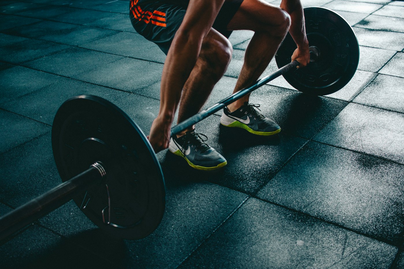 A person gripping a loaded barbell close to the floor